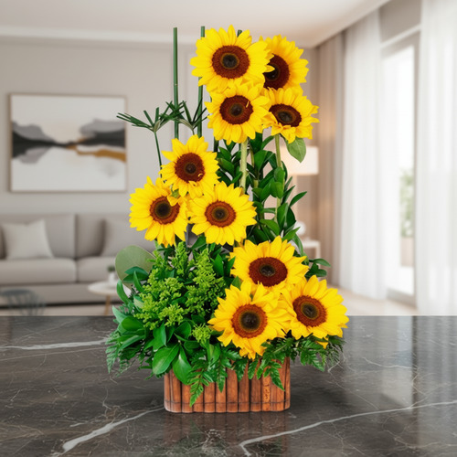 Arreglo de girasoles amarillos en mesa de mármol Arreglo floral vertical de girasoles amarillos con follaje verde en base rectangular de madera sobre mesa de mármol en sala moderna