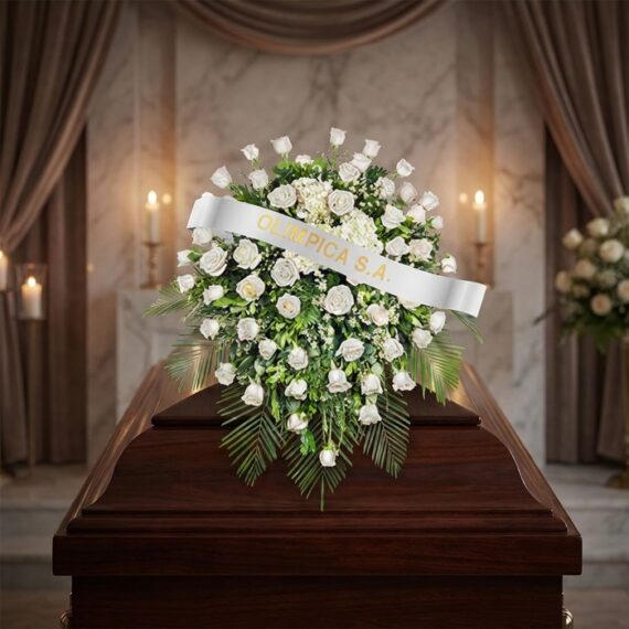 Cubre caja fúnebre Bernardita con rosas blancas y follaje verde sobre un ataúd de madera oscura, en un entorno elegante y sol